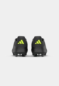 Black soccer cleats with a textured finish and contrasting neon green accents. Features three stripes on the heel for branding.