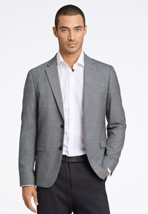 Grau blazer aus strukturiertem Stoff, mit zwei schwarzen Knöpfen und schmalen Revers, kombiniert mit einem weißen Hemd sowie schwarzem Gürtel und Hose.