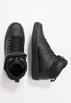 Paire de baskets montantes noires avec lacets et une sangle velcro, une chaussure vue de dessus et l'autre de côté sur fond blanc.