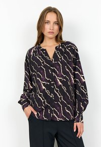 Svart blus med ett vågigt lila och krämfärgat mönster, knappar fram, v-ringning och långa ärmar. Tillverkad av ett lätt, texturerat tyg.