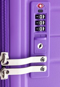 Cerniera viola della valigia con lucchetto approvato TSA, dotata di un tamburo numerico e un foro per la chiave. Le linguette in metallo della cerniera aumentano la durata.