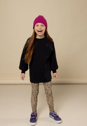 Zwarte sweatshirt met lange pofmouwen, een roze hartdetail, gecombineerd met een legging met luipaardprint en paarse sneakers met banden.