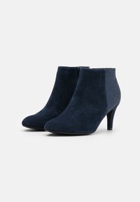 Marineblaues Wildleder-Ankle-Boots mit spitzem Zehenbereich und einem mittelhohen Absatz. Die Seiten haben ein gestepptes Stoffpaneel für Kontrast.