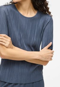 Top a costine blu navy con scollatura rotonda e maniche corte. Il tessuto ha una consistenza liscia e presenta righe verticali.