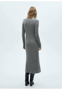 Robe longue et ajustée en tricot gris côtelé, avec des manches longues et une silhouette droite, s'étendant jusqu'au mollet.