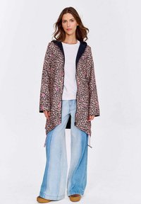 Růžovo-černá leopardí bunda s kapucí a šňůrkami. Nositá přes bílou košili a široké džíny.