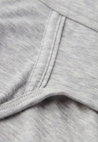 Hellgrauer Stoff mit weicher Textur, der sichtbare Nähte und ein leicht zerknittertes Aussehen aufweist. Keine Muster oder Hardware vorhanden.