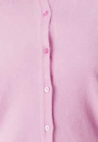 Zachte roze gebreide cardigan met zichtbare gestructureerde stof en een verticale rij bijpassende roze knopen.