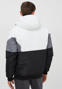 Giacca imbottita con un design a blocchi di colore, sezione bianca, grigia e nera, un grande cappuccio e polsini e orlo a costine.