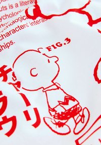 White fabric featuring a red illustration of a character with a round head and small body, dressed in a shirt and shorts, alongside Japanese text.