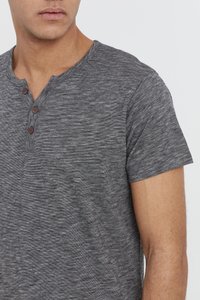 Grå kortærmet henley-shirt med et tekstureret, spraglet mønster. Har en knaplukning med tre brune knapper og en rund halsudskæring.