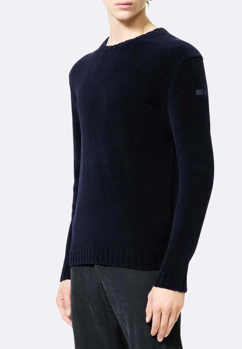 Maglione lavorato a maglia blu navy con scollo rotondo, orlo a coste e tessuto strutturato. Presenta un accento di logo discreto sulla manica sinistra.