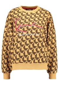 Sudadera amarilla con patrón geométrico negro, bordado en estilo firma rojo y texto blanco que dice "1989 EST. BROOKLYN, NYC" en el frontal.