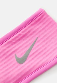 Roze sportska traka za glavu s glatkom teksturom, sadrži srebrni Nike logo i dizajn sa šivanim rubovima.