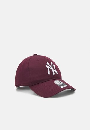 Mørkerød baseballcap med hvid New York Yankees-logo og et '47 brand-klistermærke på den buede skygge mod en lys baggrund.