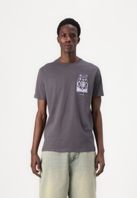 Grå bomulls t-shirt med korta ärmar, som har en färgglad grafisk design på vänster bröst som visar en sol och blommiga inslag.