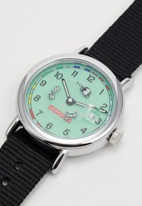 Orologio tondo con quadrante verde menta, lunetta in argento, cinturino in tessuto nero e icone a tema Monopoly che indicano le ore.
