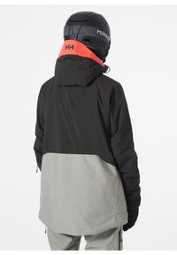 Skijacke in Schwarz und Hellgrau, mit hohem Kragen, Reißverschlusstaschen und einer Kapuze mit einem leuchtend orangen Akzent auf der Rückseite.