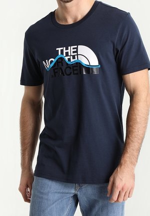 Navyblå bomulds T-shirt med "THE NORTH FACE" logo i hvid og sort, med et buet grafisk design i teal. Korte ærmer og rund halsudskæring.