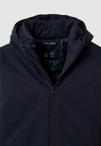 Veste imperméable bleu marine avec capuche, dotée d'une fermeture éclair à l'avant et d'une doublure intérieure douce, étiquetée "CALLIOPE" à l'intérieur du col.