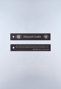 Sorte rektangulære mærkater med hvid tekst, der læser "Italian Yarn" og produktbeskrivelse, begge med et hul på venstre side og New Mill-logo.