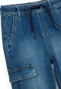 Pantalones jogger de denim en azul con cinturilla elástica, cordón regulador, bolsillos frontales y bolsillo cargo lateral. Detalles de costura.