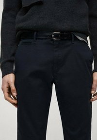 Pantaloni dark navy dintr-un material neted, cu o croială slim, buzunare frontale și o curea neagră cu accent de cataramă argintie.