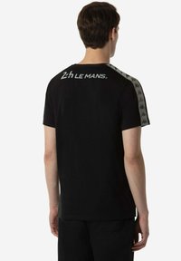 Zwart katoenen T-shirt met ronde hals, korte mouwen en Kappa-logo-accenten op de schouders. "2h LE MANS" bedrukt op de bovenrug.