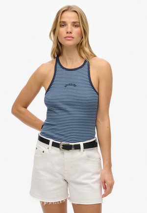 Niebiasto-biała w paski bezrękawnik z wysokim dekoltem, w zestawieniu z białymi szortami dżinsowymi o postrzępionych krawędziach i czarnym paskiem.