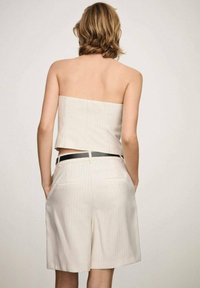 Beige, ternet strapless top parret med matchende højtaljede shorts. Har et sort bælte og to baglommer på shortsene.
