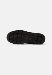 Suola di sneaker in gomma nera con battistrada testurizzato per la presa, caratterizzata da motivi rettangolari e scanalature per la trazione.