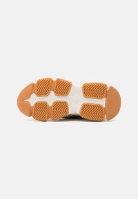 Shoe sole with a herringbone pattern, featuring orange rubber segments and white segments; textured surface for grip and durability.