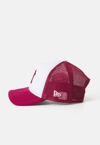 Cappellino trucker rosa e bianco con rete sul retro, visiera curva, logo in rilievo sulla parte anteriore e chiusura a scatto regolabile.