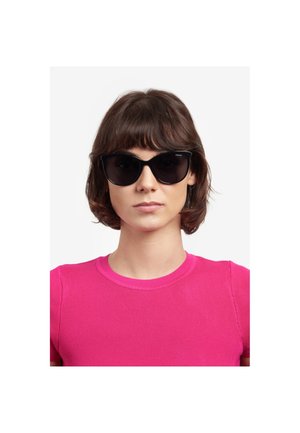 Occhiali da sole neri a forma di occhi di gatto con lenti scure, caratterizzati da una finitura lucida. Indossati da una persona con una maglia aderente a costine di un vivace colore rosa.