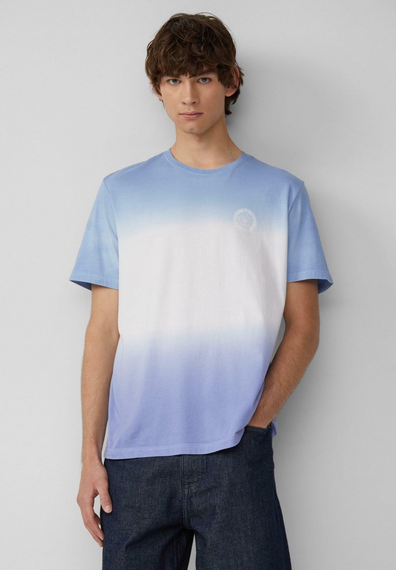 Blaue Gradient-T-Shirt aus Baumwolle, das von einem hellen Blau oben zu Weiß übergeht. Verfügt über kurze Ärmel und ein dezentes Logo auf der Brust.