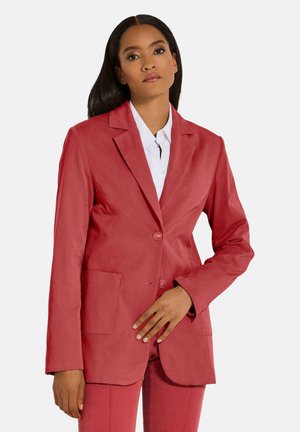 Roter Blazer aus strukturiertem Stoff, mit einer Zwei-Knopf-Front, Reverskragen und zwei vorderen Taschen, getragen über einem weißen Hemd.