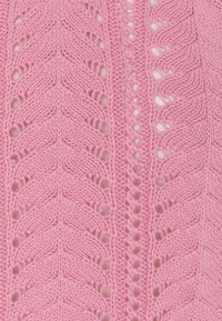 Tessuto di maglione lavorato a maglia di un vivace rosa brillante, caratterizzato da un motivo a zigzag con aperture e dettagli testurizzati lungo il centro e i bordi.