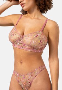 Vaatteet ovat vaaleanpunaiset läpinäkyvät bralette ja matching läpinäkyvät bikinit, joissa on kukka-embroidery, säädettävät olkaimet ja värikkäät kukkakuviot. Pehmeä rakenne.