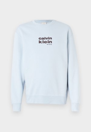 Világoskék pulóver puha anyagból, kerek nyakkivágással és hosszú ujjakkal. Elöl sötét betűkkel "calvin klein" és "New York City" felirat található.