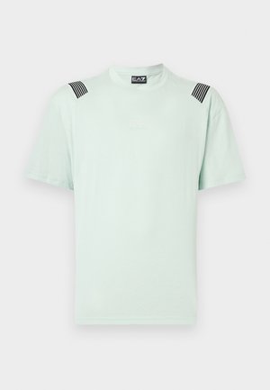 T-shirt verde menta chiaro realizzata in tessuto morbido, con maniche corte, collo rotondo e righe verticali nere sulle spalle con un branding discreto.