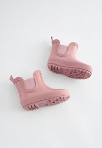 Roze waterdichte enkellaarsjes met een gladde rubberen afwerking, een gestructureerde zool en elastische zijpanelen voor gemakkelijk aan- en uittrekken.