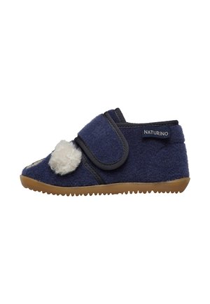 Chausson en feutre bleu marine avec un accent blanc duveteux, fermeture en Velcro et semelle en caoutchouc beige. Conçu pour le confort et une utilisation facile.