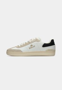 Baskets basses blanches avec des accents en suède beige, un talon noir, des lacets blancs, une semelle beige et un logo "Replay" doré sur le côté.