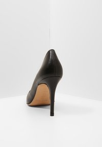 Černá kožená vysoká podpatek s špičatou špicí a štíhlým stiletto podpatkem. Hladká textura, minimalistický design a značková podrážka.