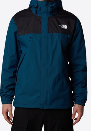 Blå og sort hættetrøjejakke med frontlynlås, elastiske manchetter og The North Face-logo på venstre bryst.