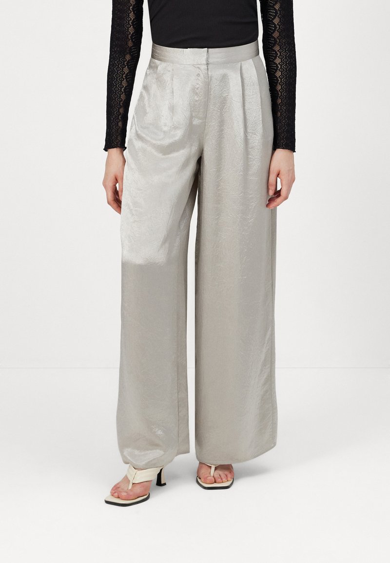 Silver wide-leg trousers made of shiny fabric with a textured finish. Features a high waist with pleats and a smooth waistband.