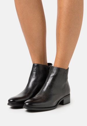 Schwarze Lederstiefeletten mit glatter Textur, runder Spitze, niedrigem Blockabsatz und seitlichen Reißverschlussdetails.