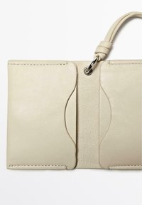 Light beige leather wallet with two curved pockets, textured center, and silver hardware loop. Smooth finish with visible stitching details.