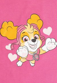 Illustrazione di un cane con pelo giallo, dettagli rosa su uno sfondo rosa, che indossa un distintivo e circondato da cuori.