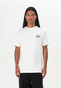 White cotton t-shirt with short sleeves, featuring a small colorful graphic of an alien spaceship on the left chest area.